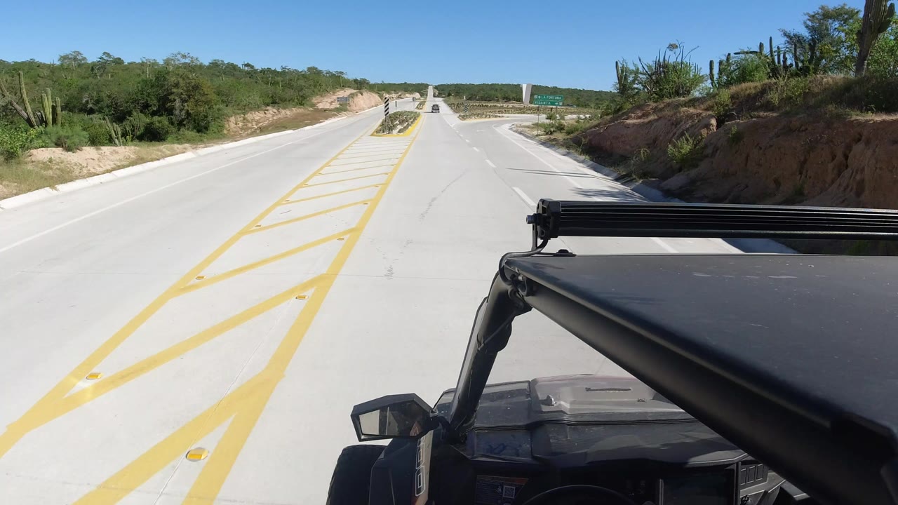 Concrete road with yellow markings and vehicle roof in foreground