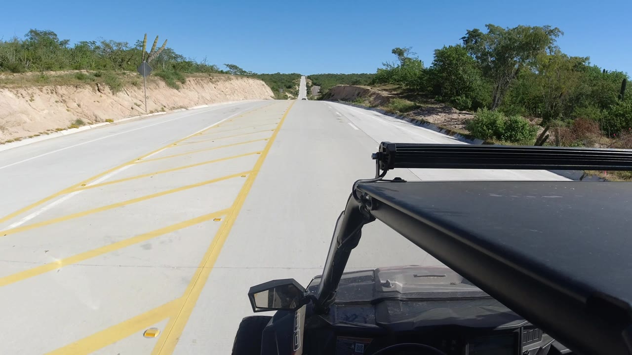 Two-lane road with diagonal yellow markings and SUV roof at the lower right.