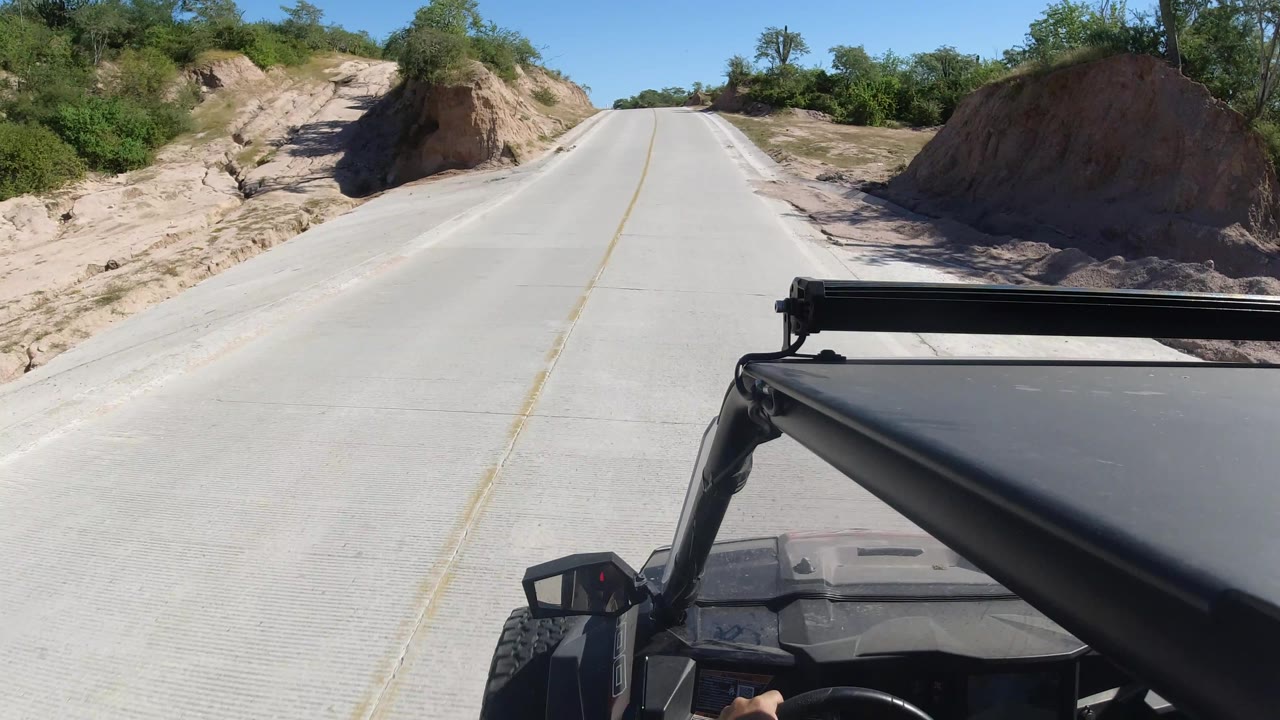 Road climbing gently between sandy cuts and vegetation