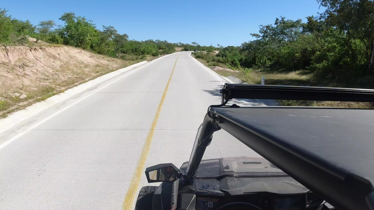 SUV hood and roof rack beside an empty sunlit highway