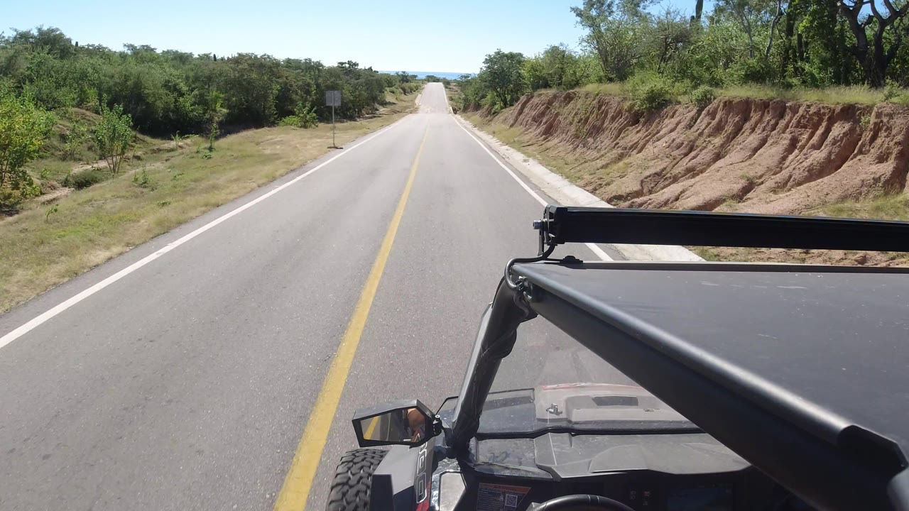 Road ahead with SUV hood and roadside sign visible.