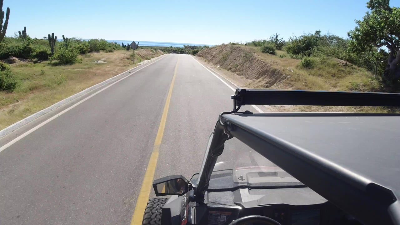 Forward road view over a jeep roof on a sunny rural highway.
