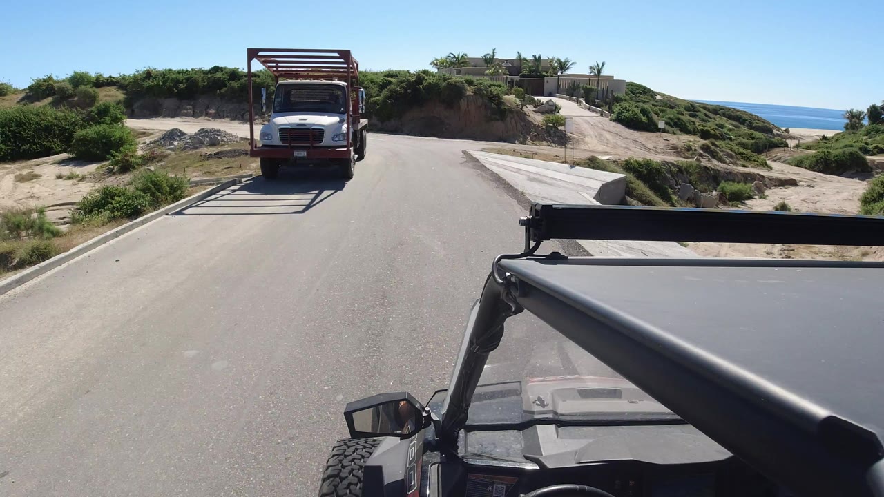 Onboard vehicle view approaching a flatbed truck on a sunlit road