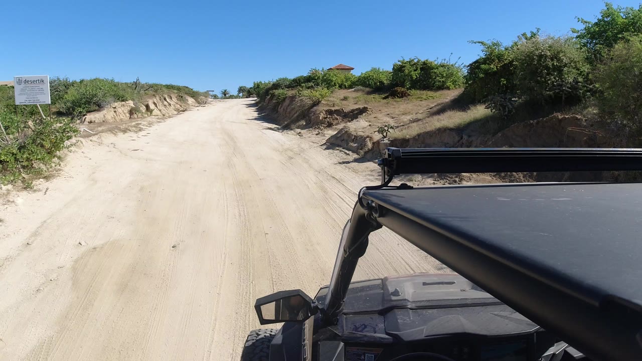 Sandy dirt road seen past a vehicle roof and roll bar