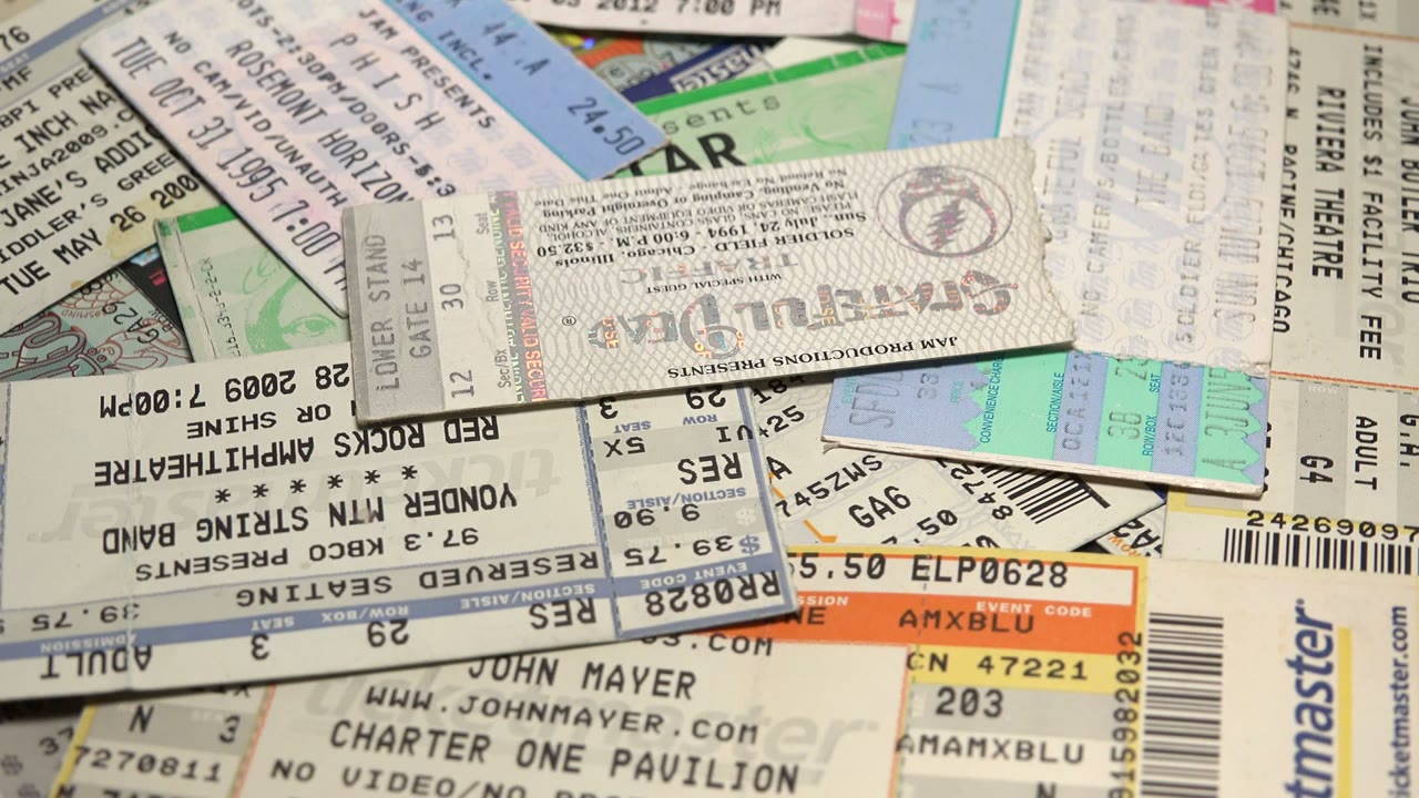 Pile of paper event tickets with visible barcodes and venue text.