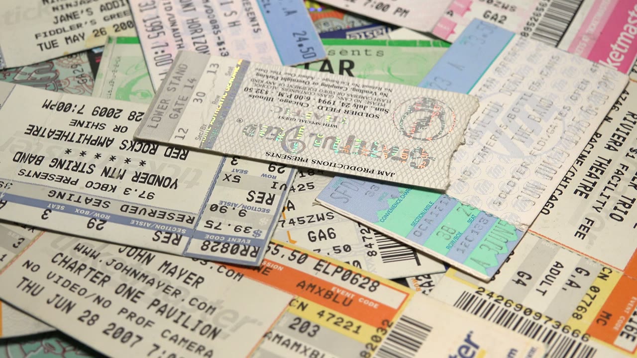 A later angle of the rotating ticket spread shows orange ticket edges, pale receipt-like stubs, barcodes, and no visible people.
