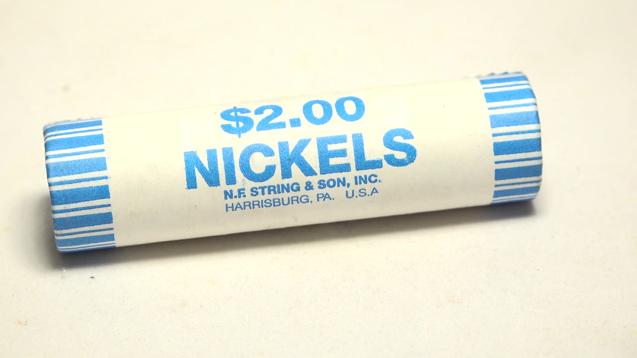 The roll has rotated to a slight angle, keeping the "$2.00 NICKELS" text readable against the plain pale surface with no visible people.