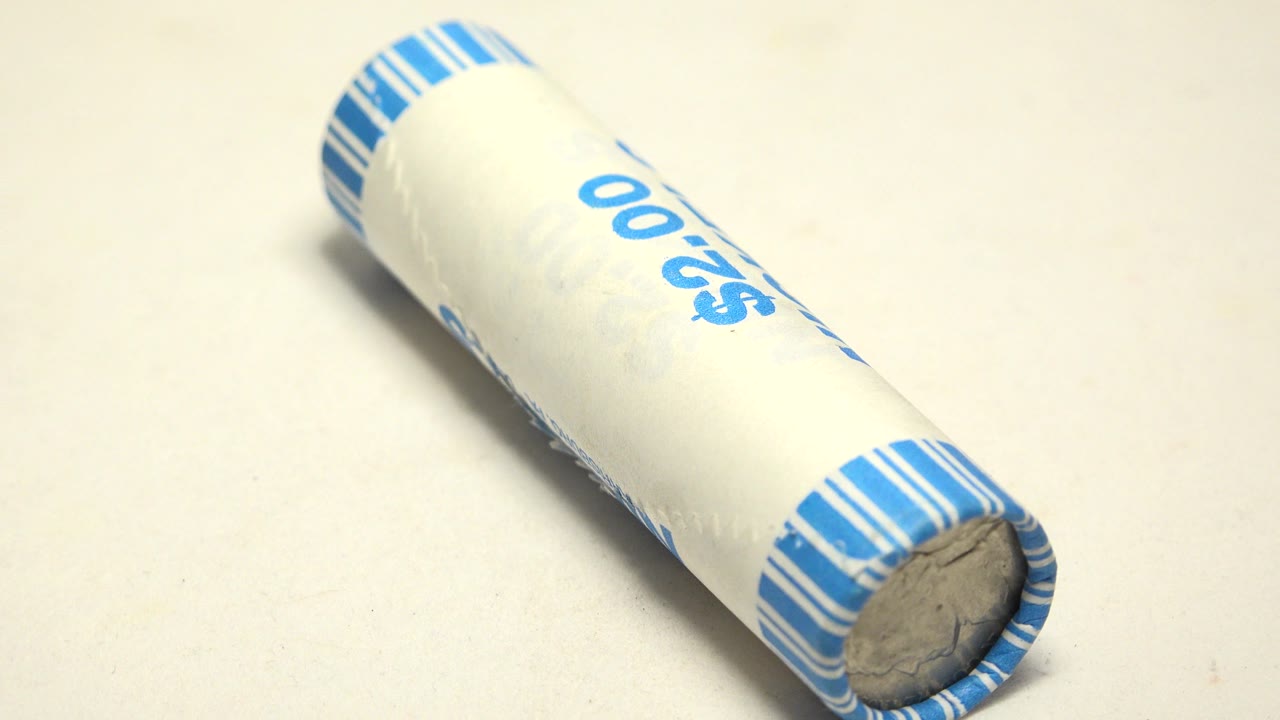 A white cylindrical tube with blue striped end bands sits diagonally on a pale tabletop, showing part of the blue $2.00 marking and no visible people.