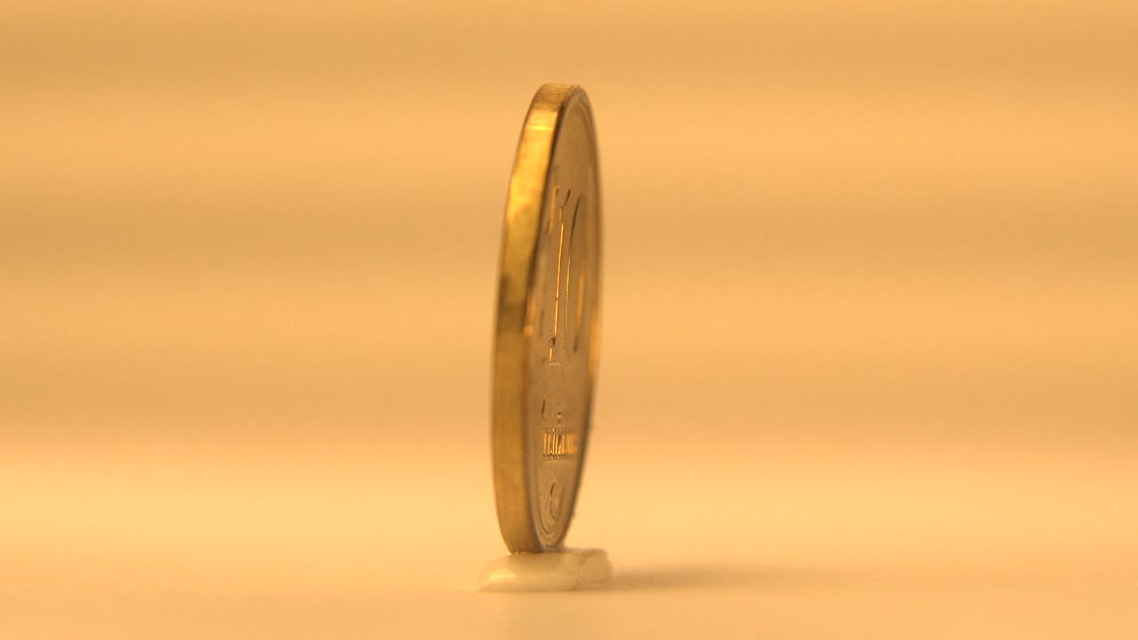 Coin viewed almost edge-on on the reflective surface.