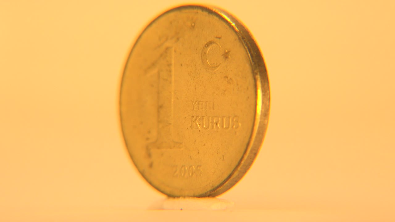The coin remains nearly front-facing with its large numeral and Kurus lettering faintly visible through soft focus, with no visible people.
