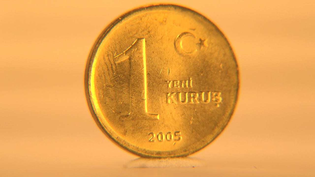 The 1 Yeni Kurus face is nearly front-on, showing the large numeral, small crescent and star mark, and 2005 date on a softly lit cream background, with no visible people.