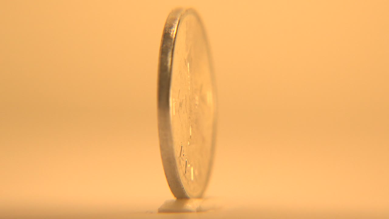 Gold-toned coin standing on its edge in warm light.