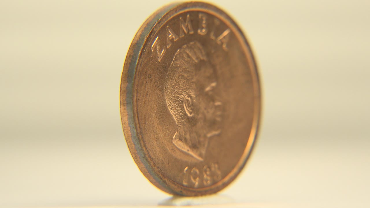Copper-gold coin upright on a glossy white surface, angled toward its portrait side with no live people visible.