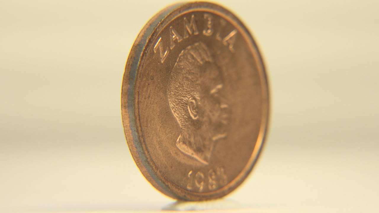 Upright coin with portrait side partly facing camera.