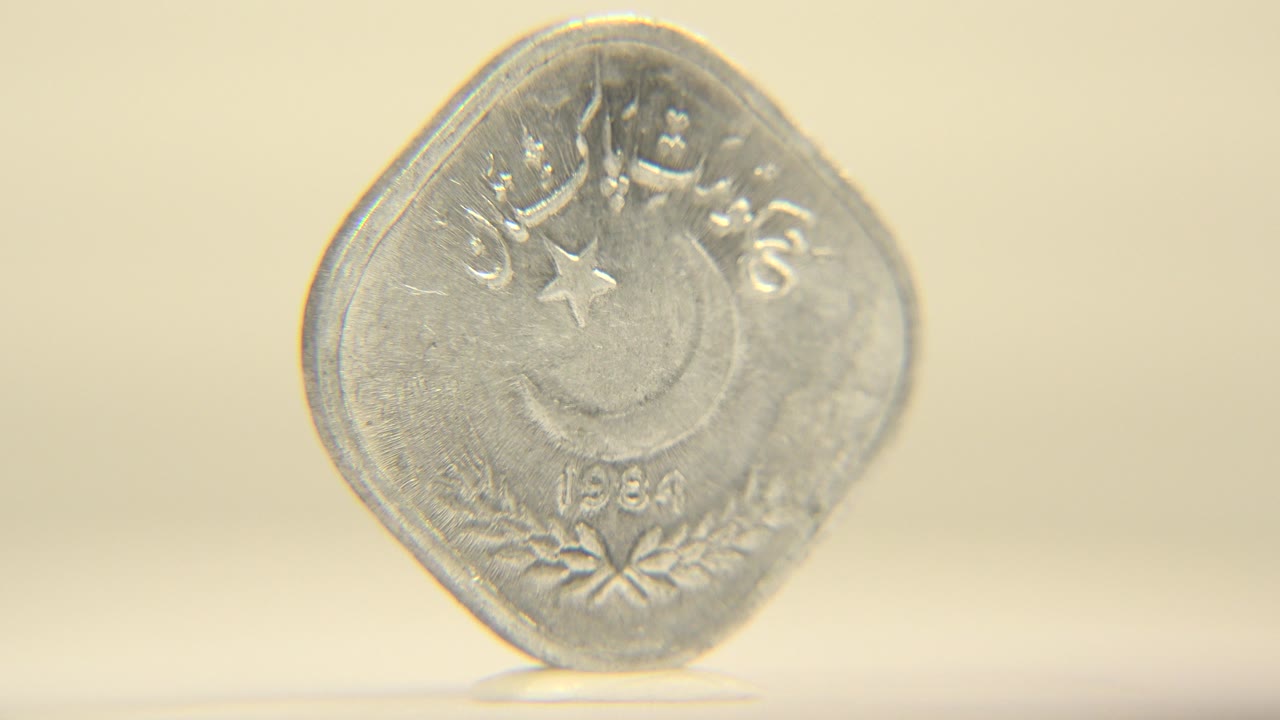 The coin remains front-facing and upright, with raised script and the crescent-and-star design catching soft warm light, with no visible people.