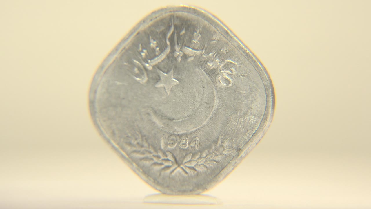 The silver coin is still mostly front-facing but angled slightly, with the date and lower wreath detail softened by shallow focus, with no visible people.