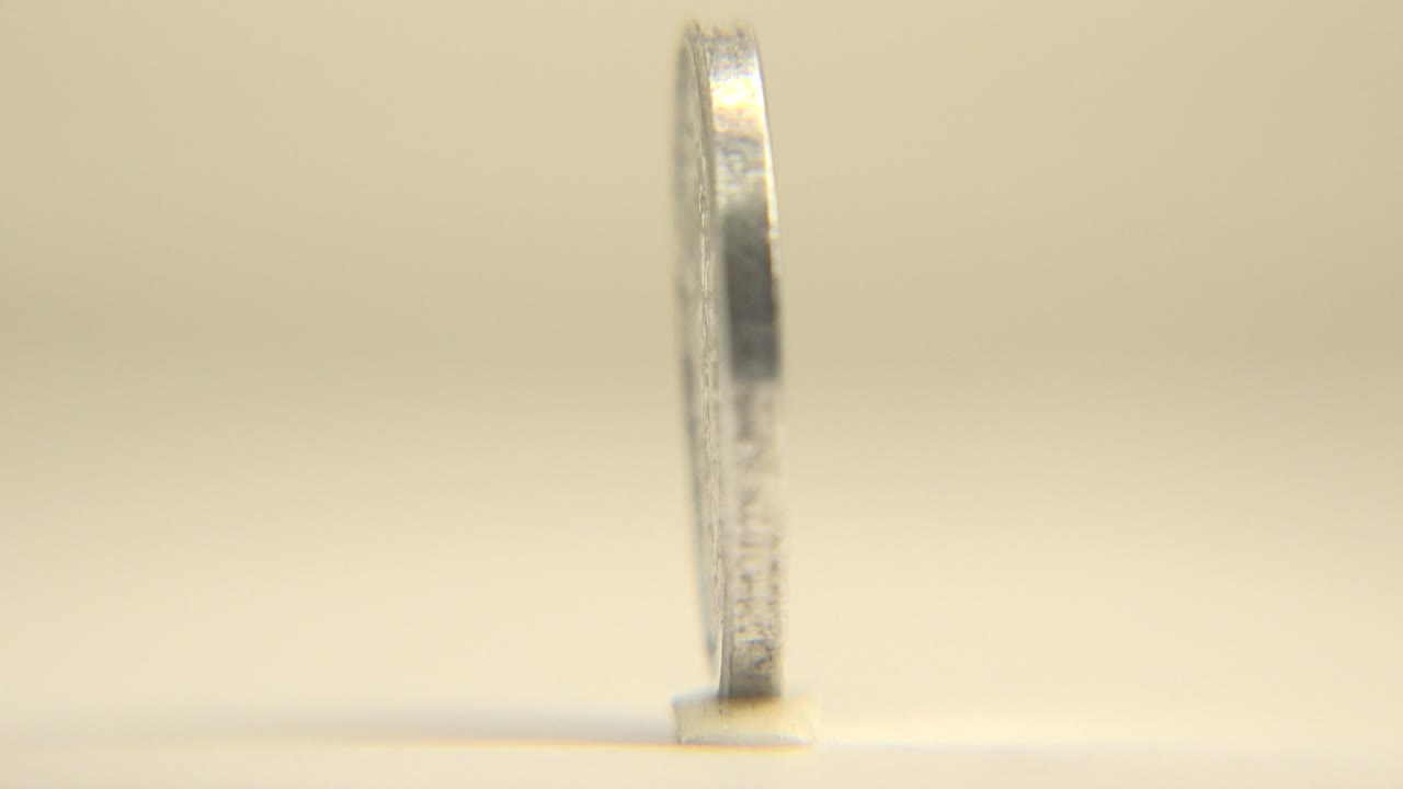 Upright silver coin shown in a narrow side profile.