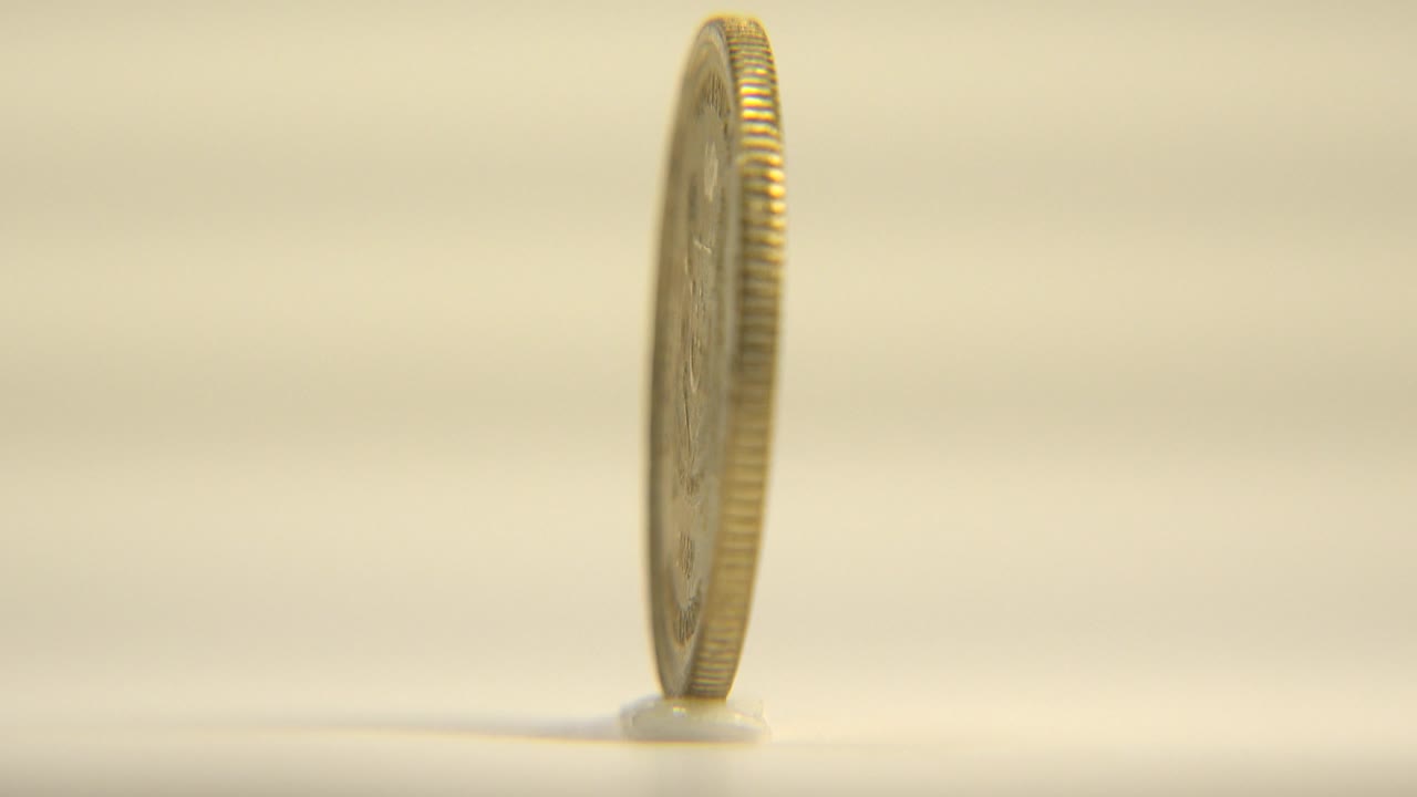 Thin edge of a five cent coin standing upright on white.
