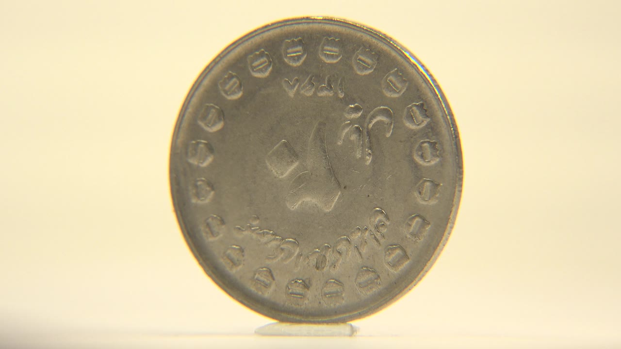 The coin appears upright and slightly farther right in the frame, with a thin base shadow on the pale surface and no visible people.
