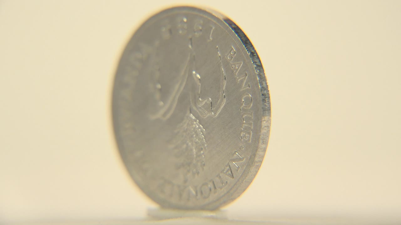 The upright silver coin remains at a shallow angle, catching soft reflections across its worn face with no visible people.