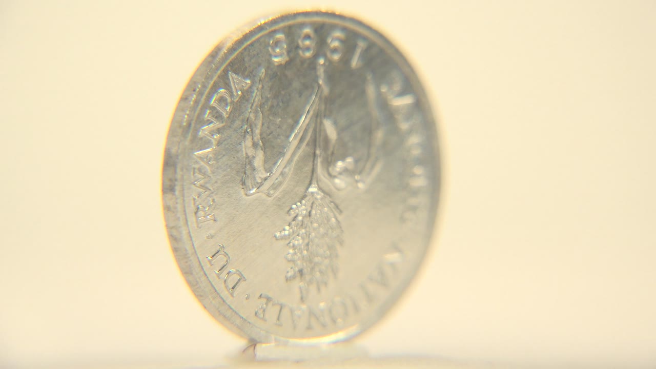 A closer angled view shows the coin's 1998 side with rim lettering, a raised motif, bright metal highlights, and no visible people.