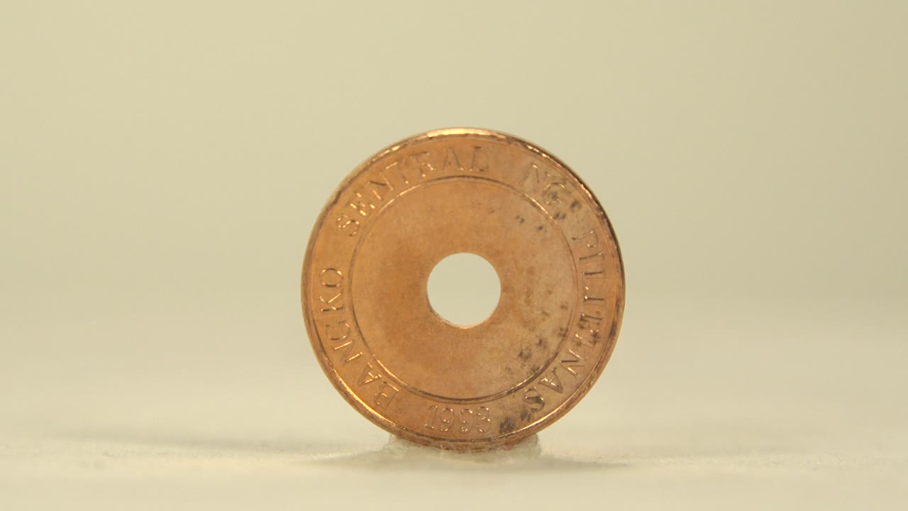 Face-on golden coin with a center hole on a flat surface.