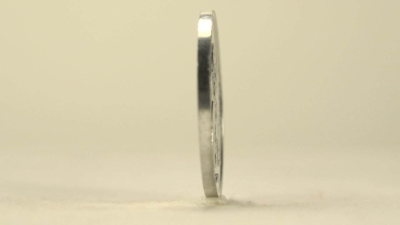 Thin edge of the upright coin shown in profile.