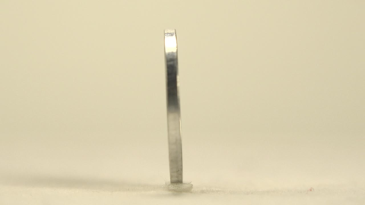 Thin silver coin from the Republic of Croatia standing upright on a pale tabletop, seen mostly from the edge with soft reflections and no visible people.