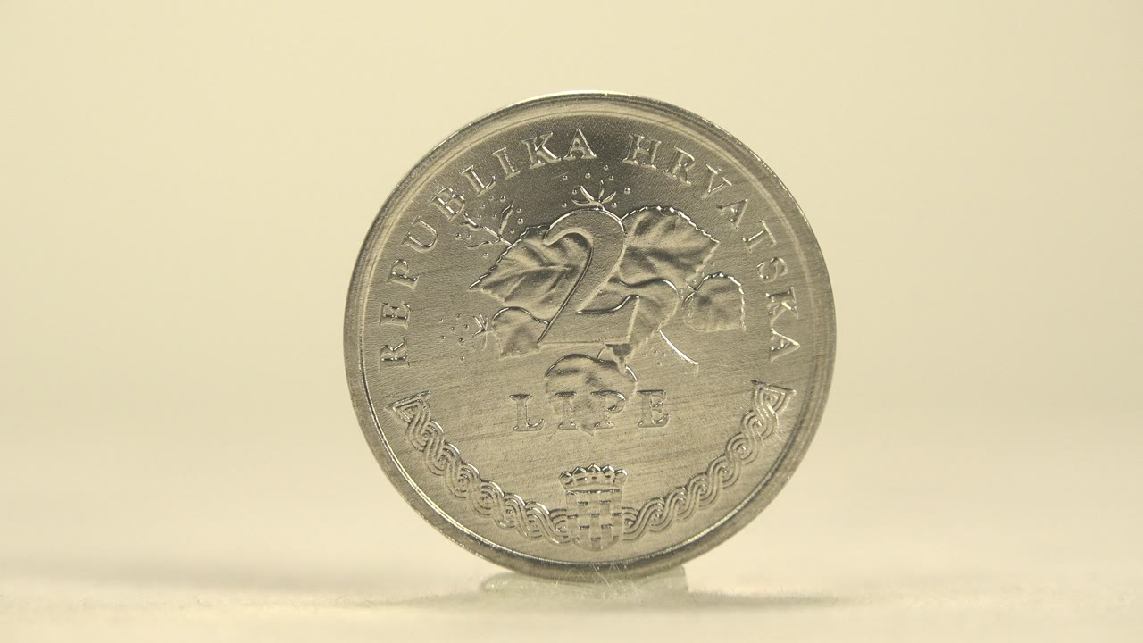 The upright silver coin remains nearly front-facing on the 25 lipa side, with soft highlights across the raised lettering and no visible people.
