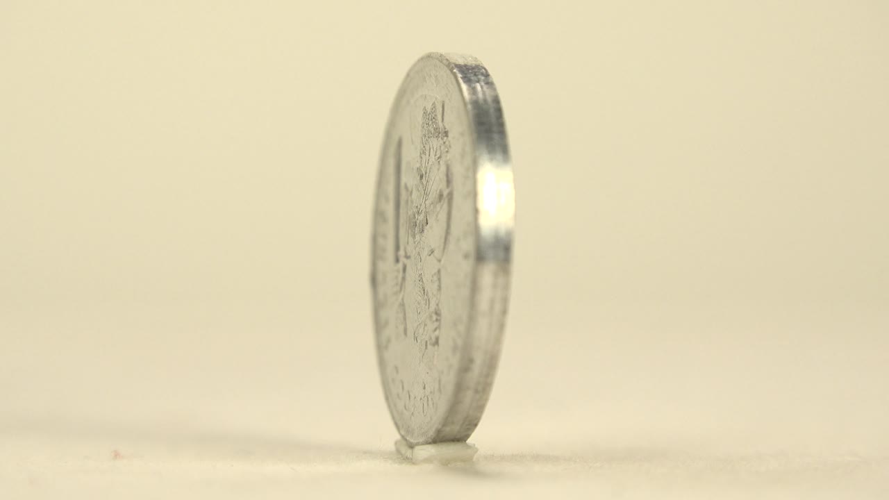 Upright silver coin seen mostly from the edge.