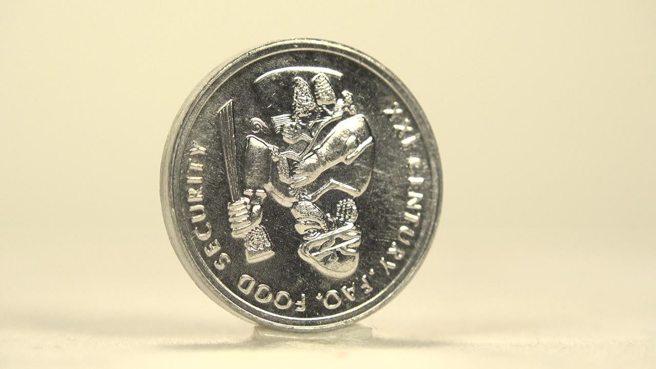 Silver coin still facing forward on a flat surface.