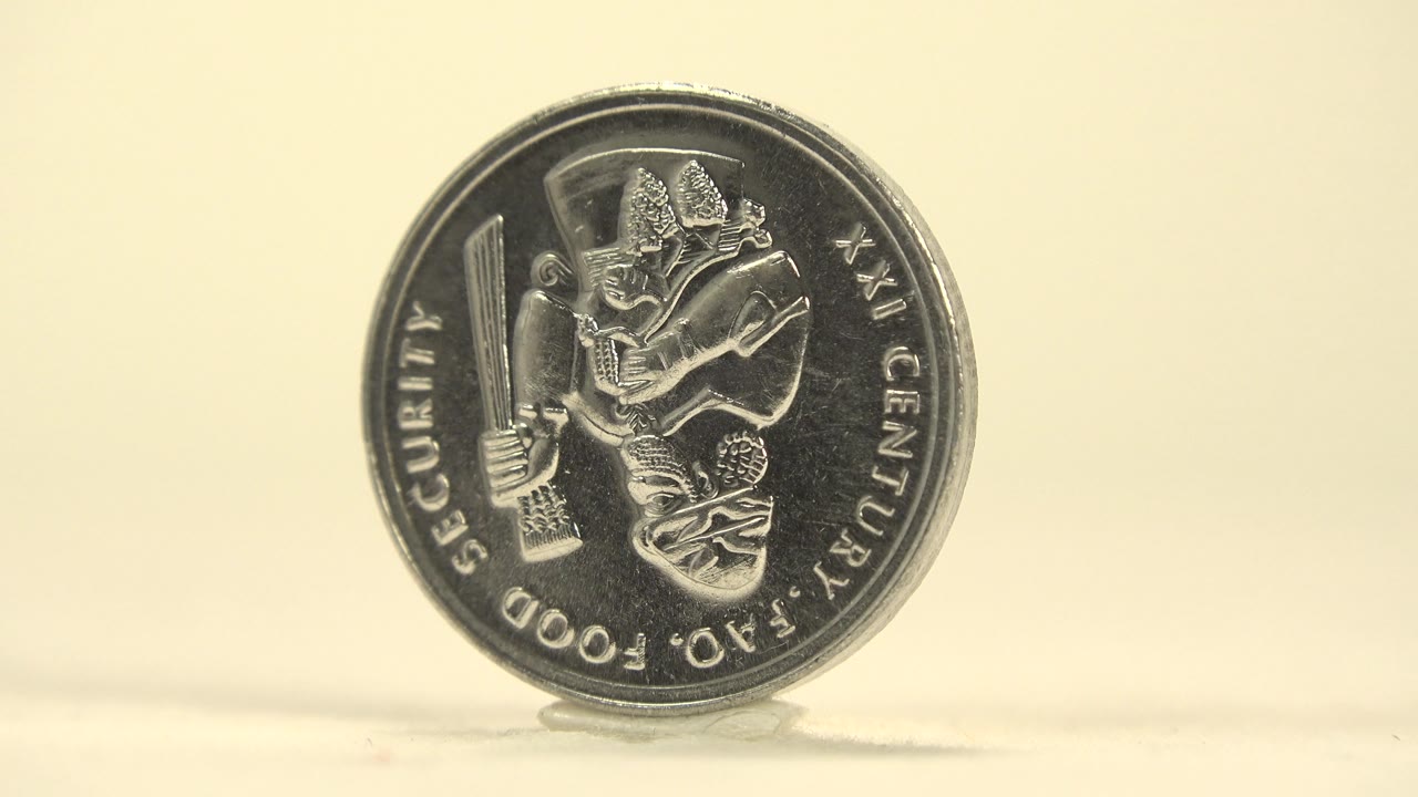 The coin turns off center, making the front design narrower and the right edge more visible, with no visible people.