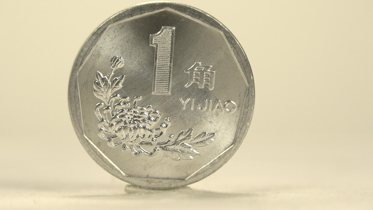 The coin remains nearly front-facing, with the number 1, Chinese characters, floral design, and shiny worn rim catching the light, with no visible people.
