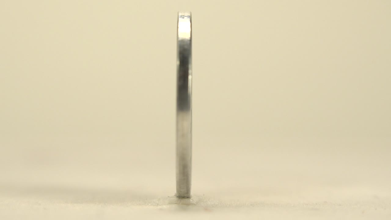 Thin coin edge standing on a pale tabletop.