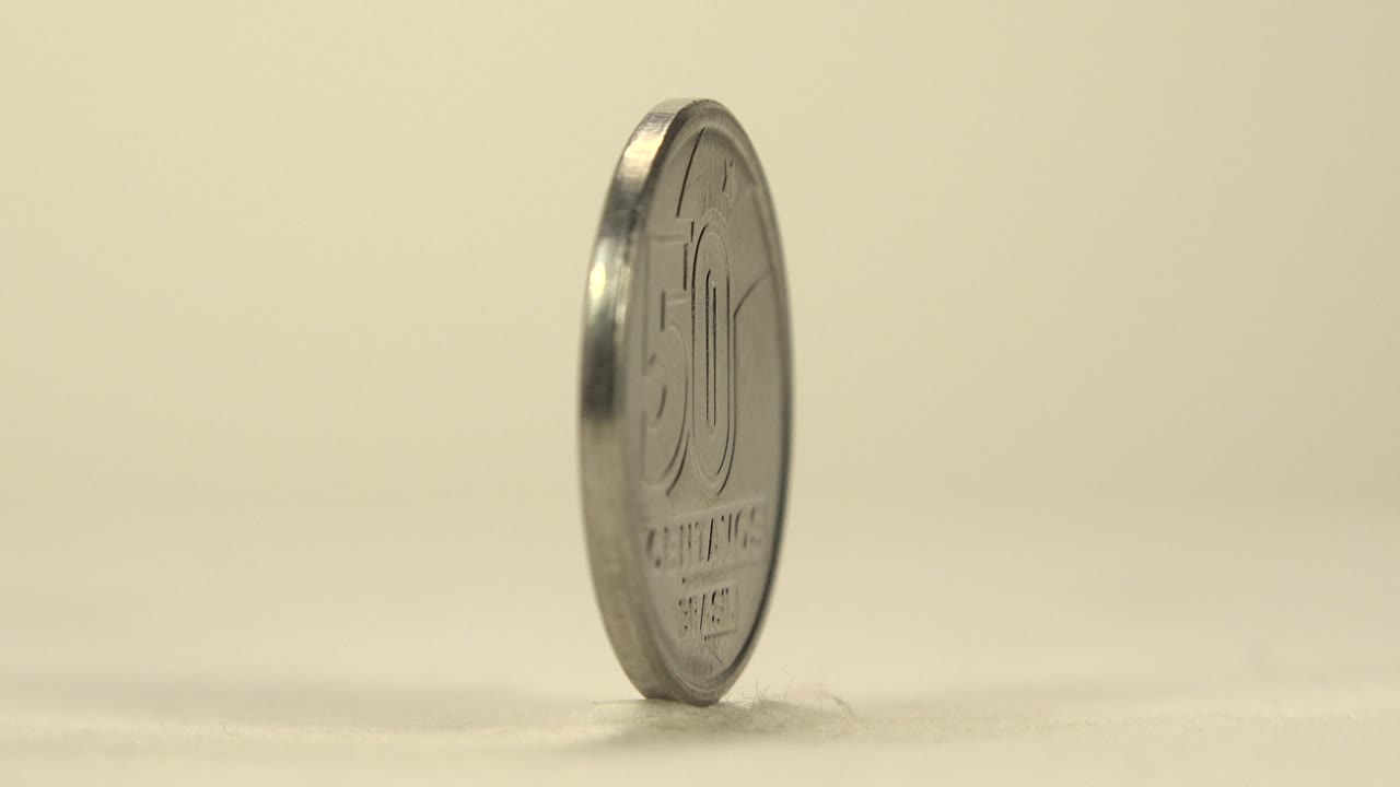 A side-angled view shows the coin upright with the 50 centavos face partly visible and the rim catching highlights, no visible people.