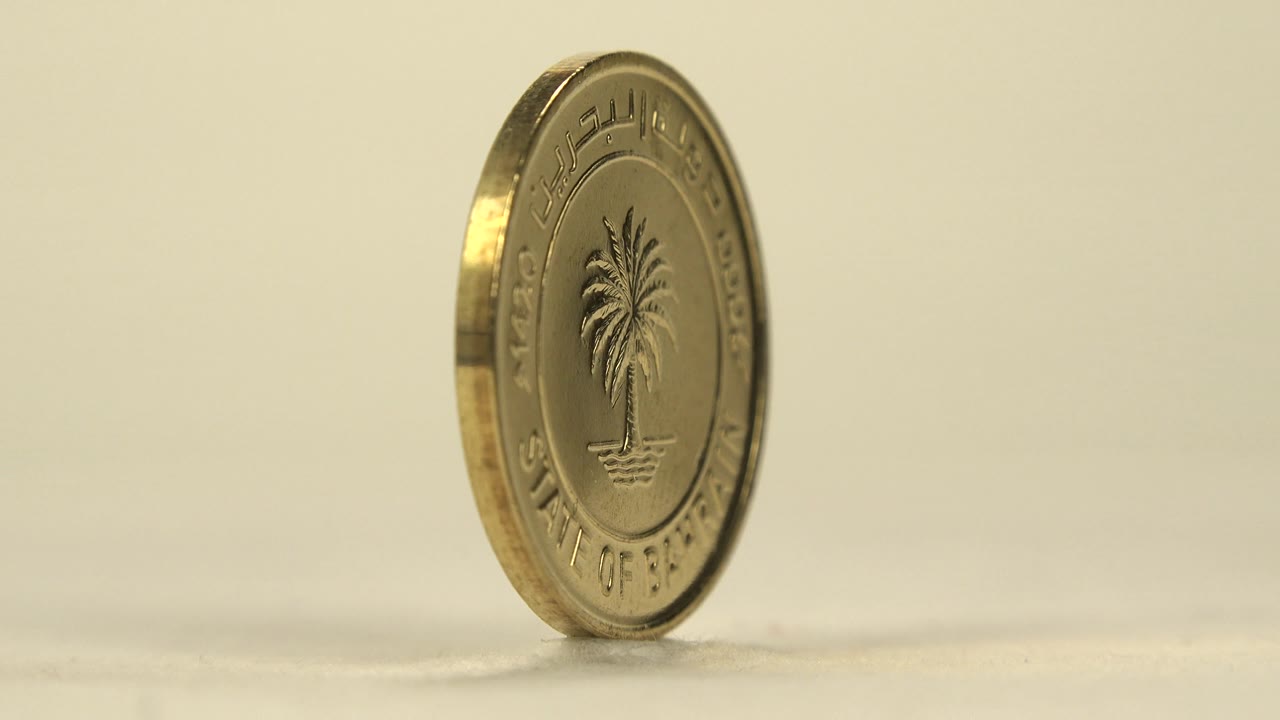 Bahrain coin upright with palm tree side partly turned away.