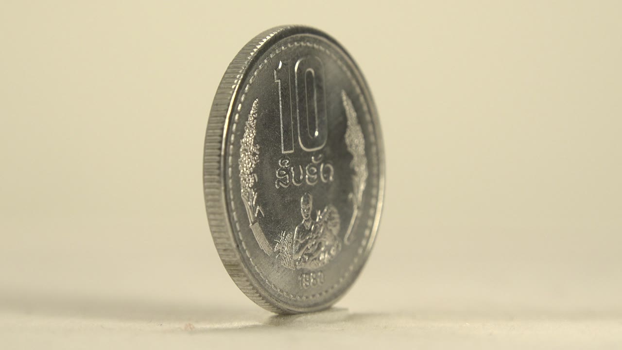 The 10R face of the silver coin turns toward the camera at a slight angle, with embossed lettering and reflective wear visible on the plate and no visible people.