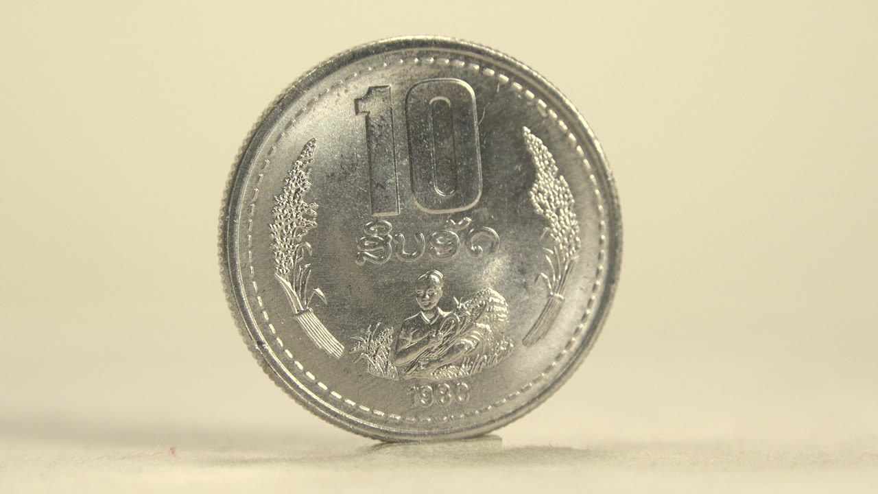 Front face of a silver 10R coin close to camera on a pale plate.
