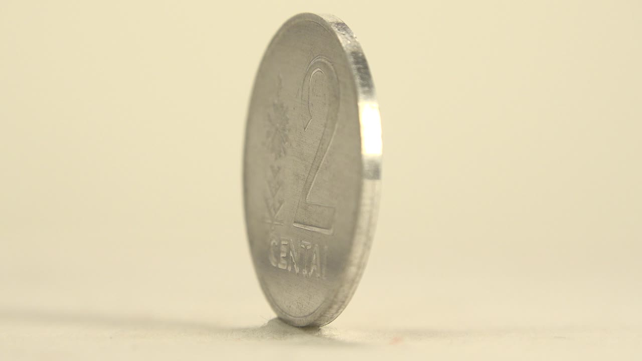 A silver 2 centai coin stands upright on a cream surface, showing the numeral side at a slight angle with no visible people.