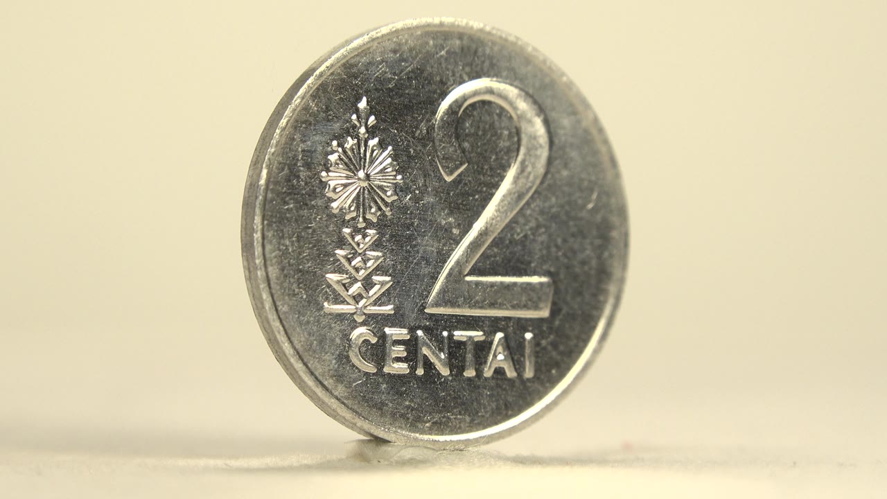 A shiny silver 2 CENTAI coin stands upright on a pale surface, showing the numeral 2 and decorative marks, with no visible people.