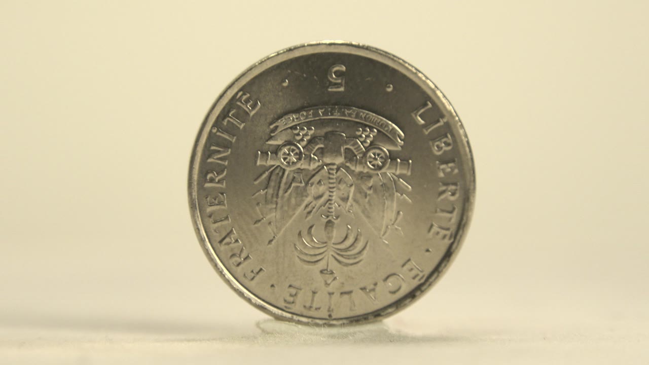Silver Haitian coin in Haiti shown upright with an emblem side facing forward on a pale surface, with warm light and no visible people.