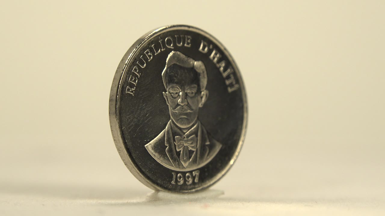 An upright silver coin shows the portrait side with 1997 visible near the bottom, set against a warm blurred background with no visible people.