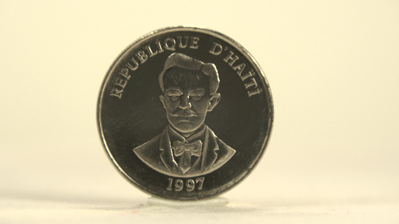 The portrait side of the coin is still readable as the body angles slightly, catching darker reflections across the silver face with no visible people.