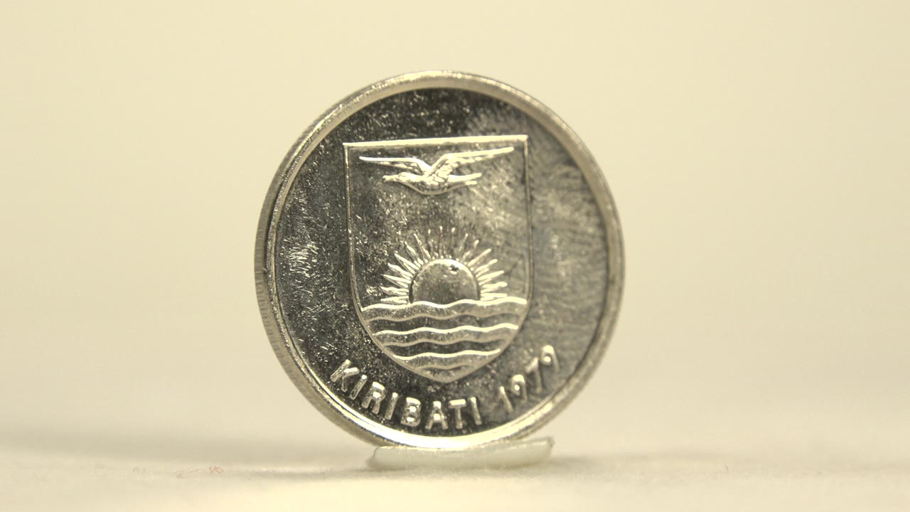 Close-up of the Kiribati 1979 side of a silver coin standing upright on a small clear stand against a pale background, with no visible people.