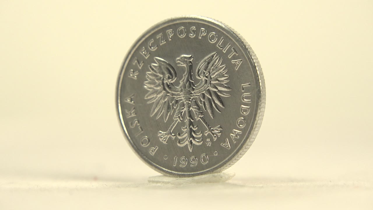The spinning coin tilts slightly away from camera while the eagle side remains readable against the soft cream background, no visible people.