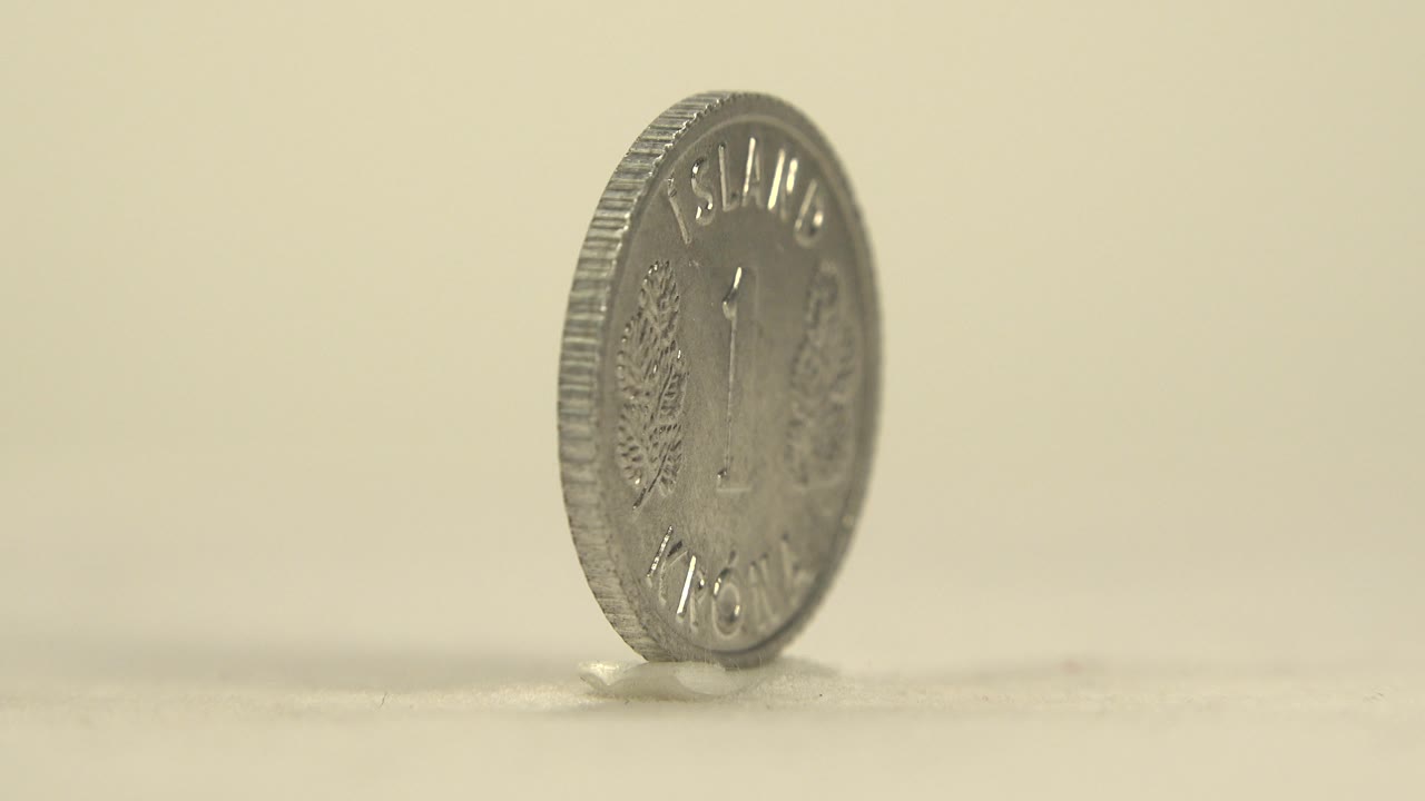 The rotating coin turns enough to reveal part of its face, including a large 1 and raised lettering, with no visible people.