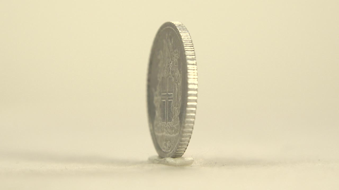 Thin edge view of the upright silver coin.