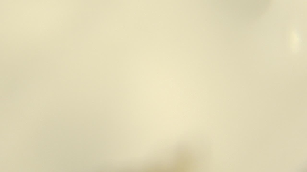 At 0:03, the frame becomes a mostly pale, soft-focus close-up with a small bright spot toward the right and no visible people.