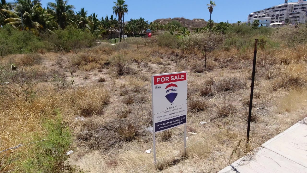 For-sale sign at the right edge of a dry roadside lot.