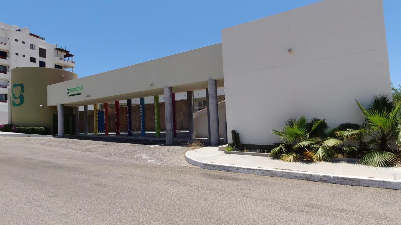 Modern concrete building beside an empty paved parking area under blue sky.